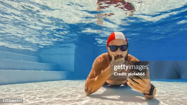 funny man selfie with mobile phone underwater: extreme telecommuting - diving into water stockfoto's en -beelden