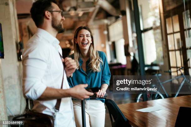 empresario y empresaria hablando y riendo en la oficina - maletín para portátil fotografías e imágenes de stock