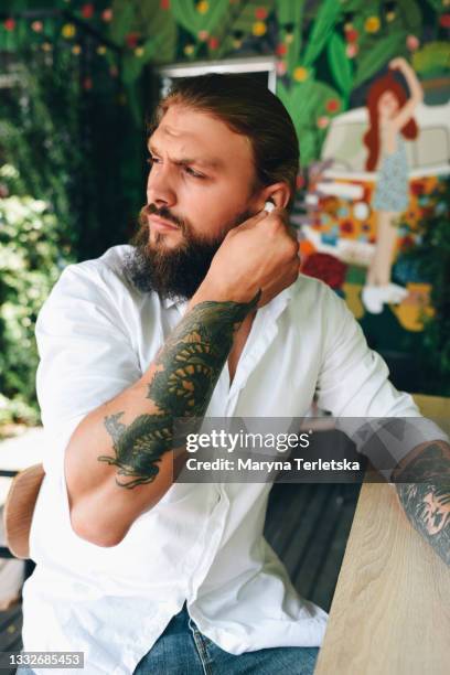 young guy puts on wireless headphones. - headphone man on neck stock pictures, royalty-free photos & images