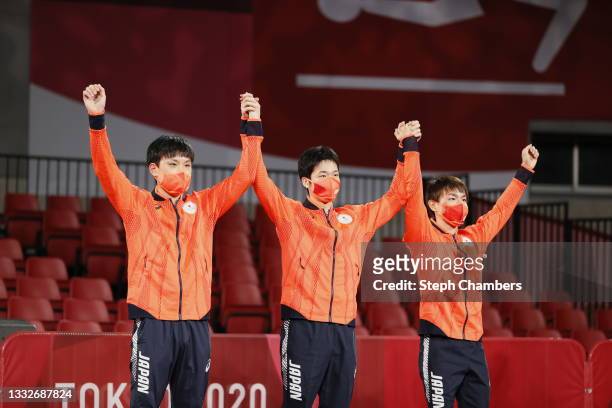 Team Japan players Harimoto Tomokazu, Mizutani Jun, and Koki Niwa wave on the podium during the medal ceremony of the Men's Team table tennis on day...