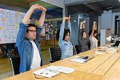 Workers doing stretching exercises in a business meeting at the office