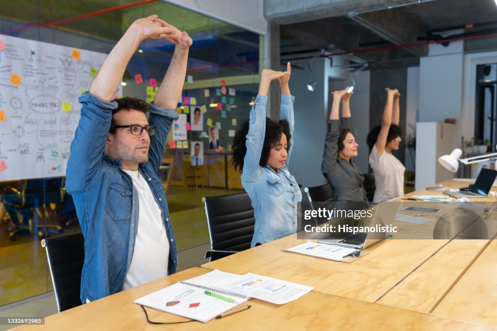 Workers doing stretching exercises in a business meeting at the office