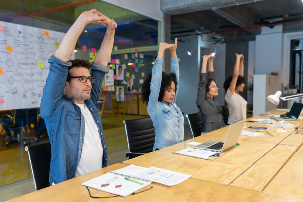 Group of Latin American Workers doing stretching exercises in a business meeting at the office - healthy lifestyle concepts