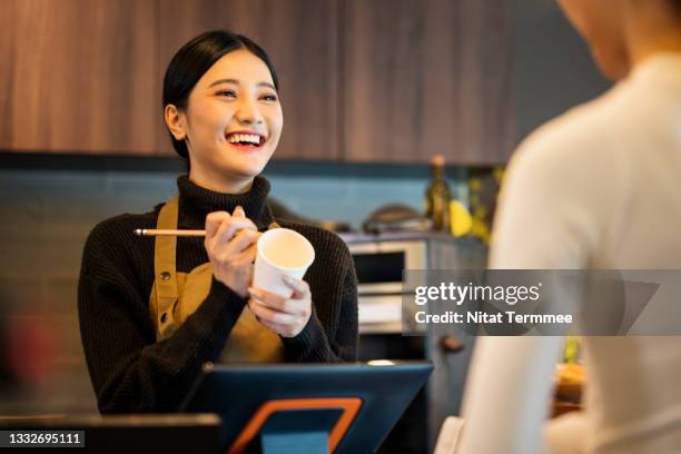 coffee shop owner taking order and writing customer name on paper cup for ordering. point of sale system, customer service, and small business solution. - asian coffee at cafe imagens e fotografias de stock