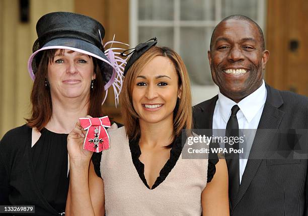 British athlete Jessica Ennis holds her MBE alongside her parents Alison and Vinny after it was presented to her by Prince Charles, Prince Of Wales...