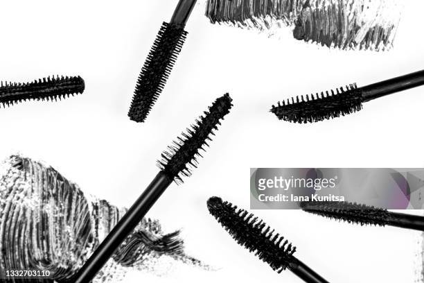 black smear mascara and brushes on white background. isolated. makeup. cosmetic products for eyelashes. closeup. beautiful pattern. - mascara stockfoto's en -beelden