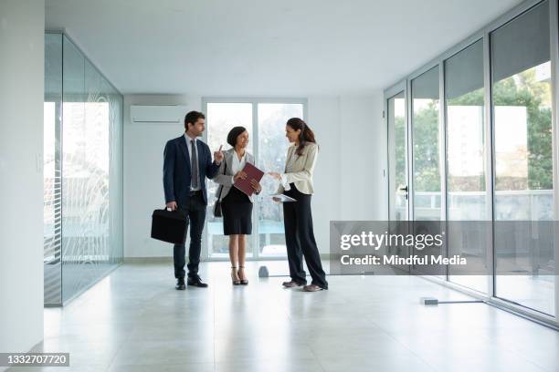 female latin real estate agent talking with businessman and businesswoman - real estate office stockfoto's en -beelden