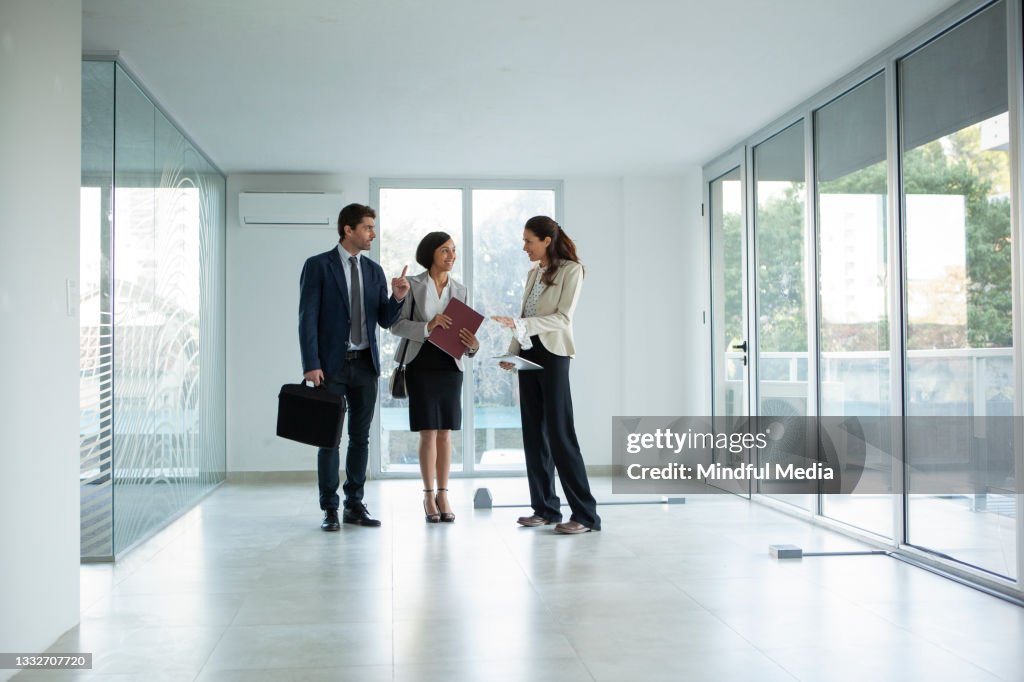 Female latin real estate agent talking with businessman and businesswoman