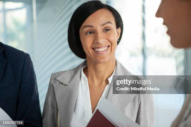 smiling latin businesswoman looking at coworker - corporate media modern bright stockfoto's en -beelden