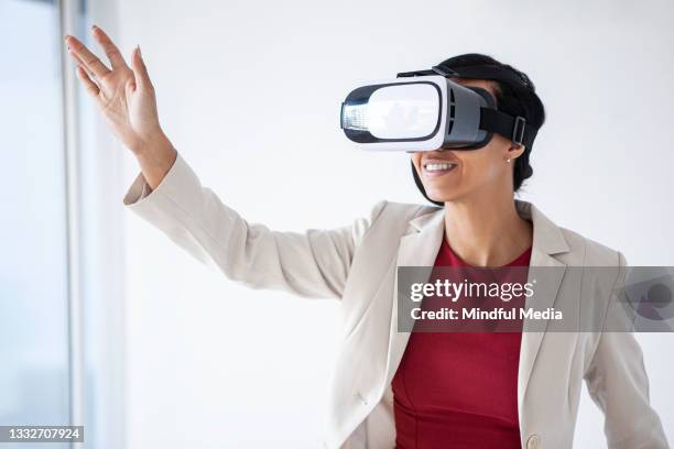 schöne lateinamerikanische frau, die versucht, etwas zu berühren, während sie eine virtual-reality-brille benutzt - erweiterte realität stock-fotos und bilder