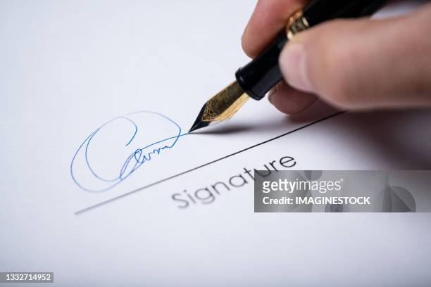 signing using a fountain pen - contrato fotografías e imágenes de stock