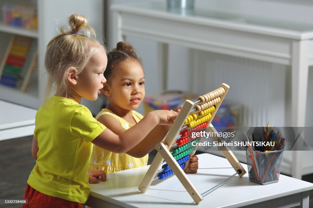 Children of different races sit together at the table and count on the abacus