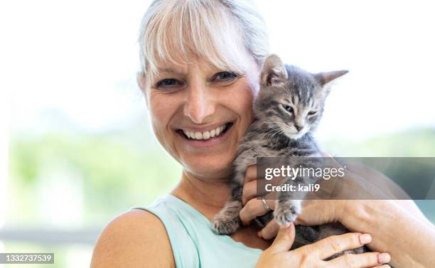 mature woman holding kitten, smiling - cat human face stock pictures, royalty-free photos & images