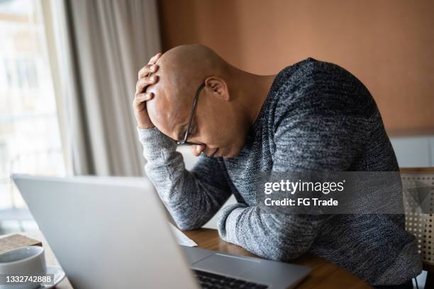 worried man using laptop working at home - uncertainty stock pictures, royalty-free photos & images