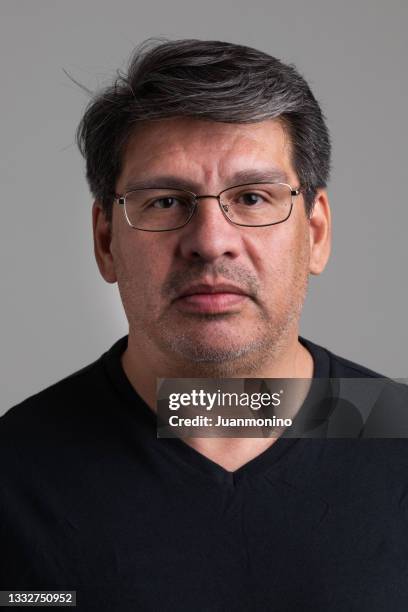 uomo maturo pensieroso che guarda la fotocamera su sfondo grigio - studio head shot serious confident looking at camera foto e immagini stock