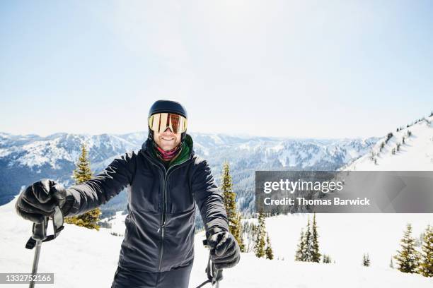 medium shot portrait of smiling male skier standing on ski slope while skiing on sunny winter morning - gafas de esquí fotografías e imágenes de stock