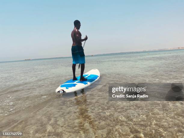 african american man on paddle board. - paddle board men imagens e fotografias de stock