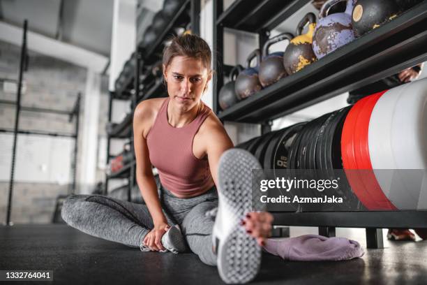 focused sportswoman doing seated hamstring stretch at gym - hamstring stockfoto's en -beelden