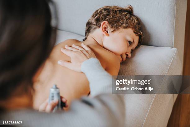 mother applies skin care cream to his son - son massage mom stock pictures, royalty-free photos & images