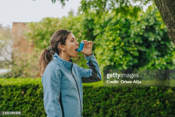 frau, die asthma-inhalator im freien verwendet - bronchial asthma stock-fotos und bilder