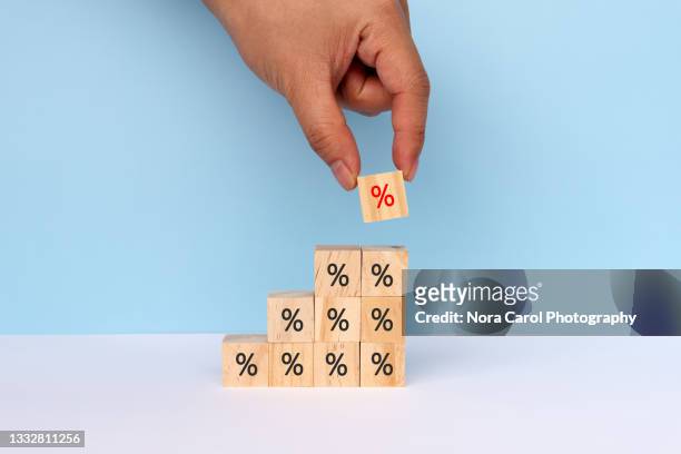 hands stacking percent signs on wood toy block - interest rate stock pictures, royalty-free photos & images