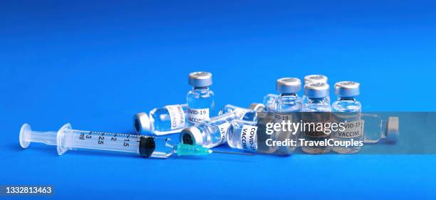 covid-19 corona virus vaccination with vaccine bottle and syringe injection tool for covid19 immunization treatment. ampoules with covid-19 vaccine on blue background. - covid 19 vaccine stock pictures, royalty-free photos & images