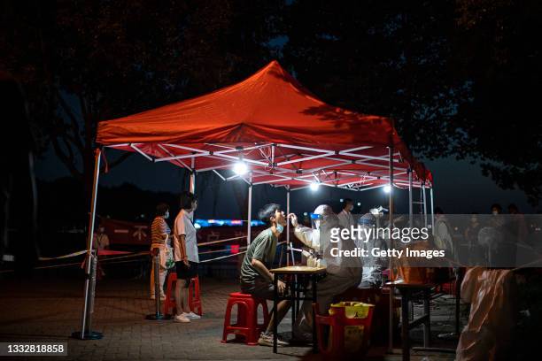 Medical worker takes samples during a mass Covid-19 test in a residential block on August 6, 2021 in Wuhan, Hubei Province, China. Local media has...