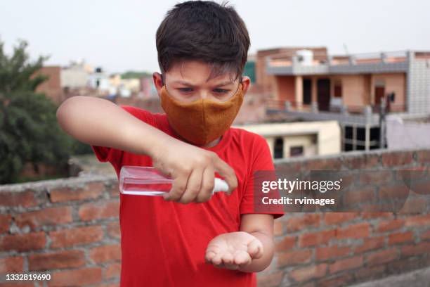 aluno da escola de ensino fundamental segurando desinfetante de mão e aplicando na mão - hand sanitiser - fotografias e filmes do acervo