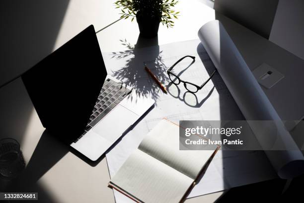 high angle view of a workplace desk with a laptop in office, a notebook and architectural blueprint on the table - desk angle stock pictures, royalty-free photos & images