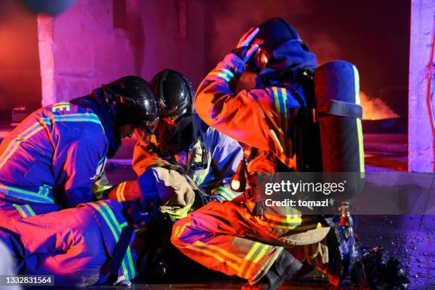 firefighters helping their injured friend - red event in stockfoto's en -beelden