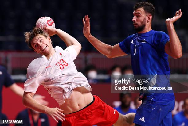 Mathias Gidsel of Team Denmark shoots at goal while under pressure from Nedim Remili of Team France during the Men's Gold Medal handball match...