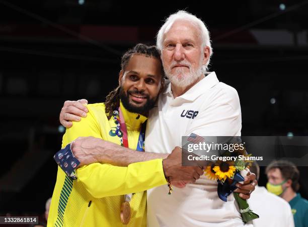 Team United States Head Coach Gregg Popovich poses with Team Australia's Patty Mills during the Men's Basketball medal ceremony on day fifteen of the...