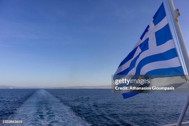 View of greek flag from ship leaving the port Tino island on April 14, 2021 in Tinos, Greece.