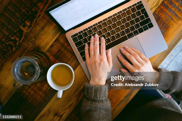 women's hands type text on the keyboard of a computer or laptop, in a cafe or coworking space. an office worker at his desk. the concept of business, freelancing, working at home. next to it is a teapot with herbal green tea, a glass. take a break. - paying employees stock pictures, royalty-free photos & images