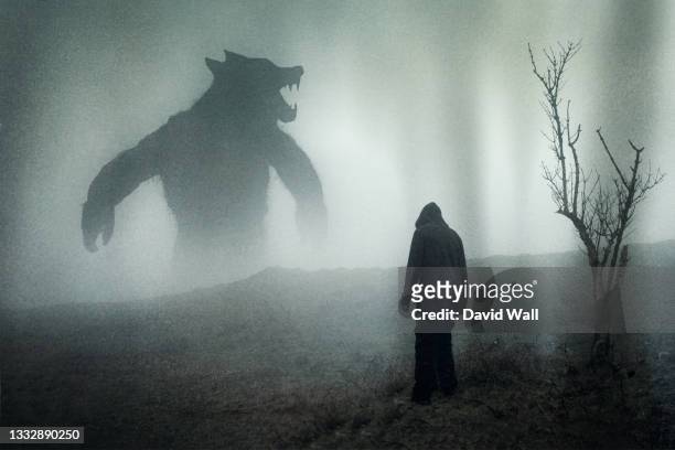 a horror concept of a man looking at a giant werewolf figure on a moody mountain side. with a grunge edit - demon fictional character stock pictures, royalty-free photos & images