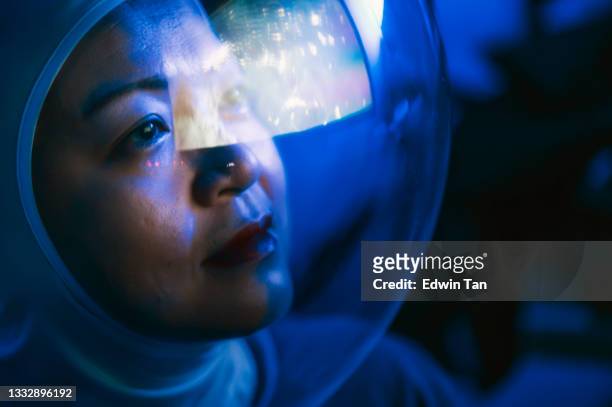 asian chinese mid adult female astronaut looking at earth through window from spaceship at outer space - chinese hero stockfoto's en -beelden
