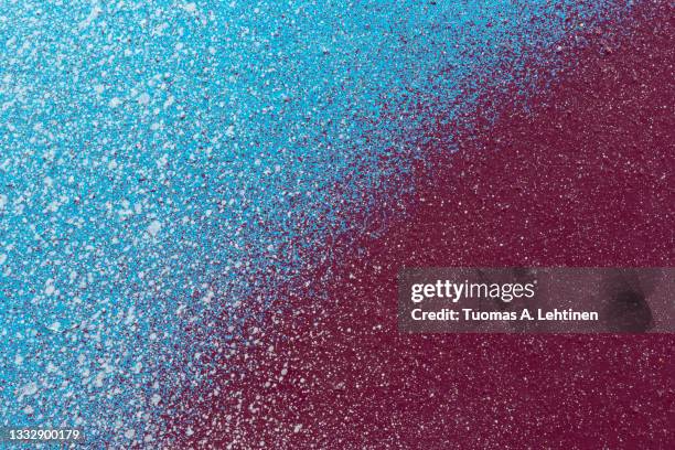 macro close-up of a light blue and burgundy red spray paint with white splashes. - burgundy stockfoto's en -beelden