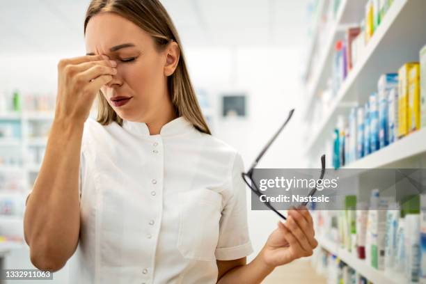 pharmacist woman with headache in drugstore - gray hair stress stock pictures, royalty-free photos & images