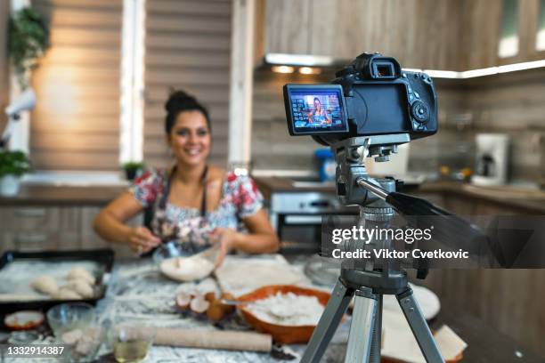woman filming vlog while kneading pastries at home in the kitchen - side hustle stock pictures, royalty-free photos & images