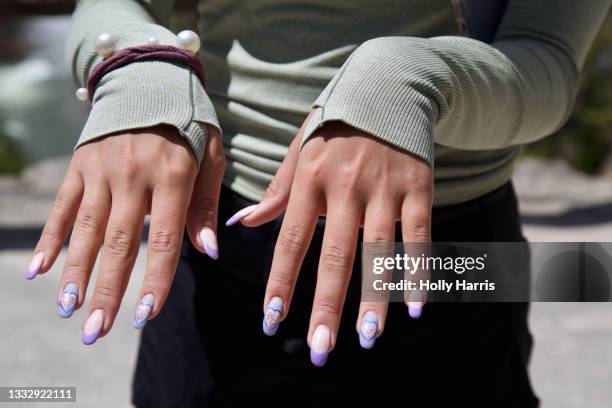 young woman showing her manicure, purple nail polish, hearts - multi coloured nails stock pictures, royalty-free photos & images