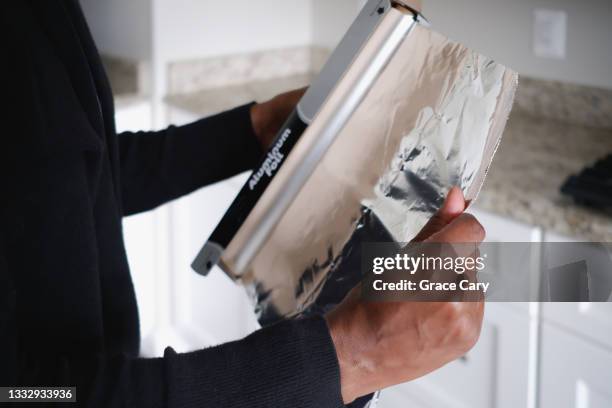 woman removes aluminum foil from container - folie stock-fotos und bilder