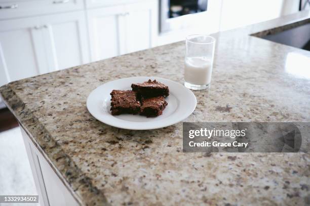 plate of fudge brownies and glass of milk on kitchen counter - dulce de azúcar y mantequilla fotografías e imágenes de stock