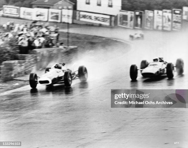 Cars speed on the rain soaked track during the Belgium Grand Prix in a scene from the film 'Grand Prix', 1966.