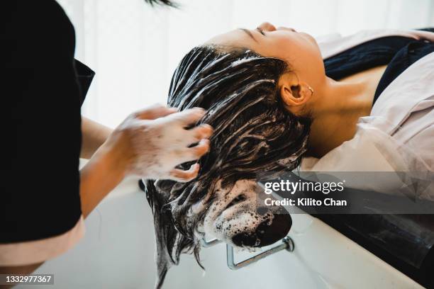 asian woman has her hair washed at a hair saloon - hair treatment stock pictures, royalty-free photos & images
