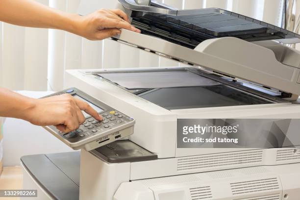 close up hand of office man press the copy button on panel to using the copier or photocopier machine in copy room for scanning document printing a sheet and xerox photocopy. - コンピュータプリンタ ストックフォトと画像