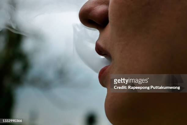 woman vaping electronic cigarette with smoke closeup. young woman smoking e-cigarette to quit tobacco. vapor and alternative nicotine free smoking concept. - e zigarette stock-fotos und bilder