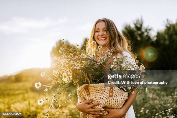 young adult woman outdoors in camomile field enjoying summer - zonnenbloem stockfoto's en -beelden