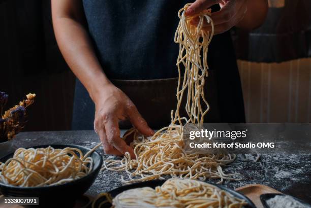 hands of woman make an egg noodle on the black table - noodle foto e immagini stock