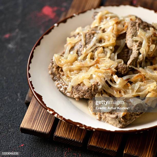 fried meat chops with onions. clay plate with hearty lunch on wooden table. close-up shot. soft focus. copy space - schnitzel stockfoto's en -beelden