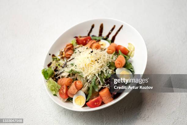 caesar salad with red fish and grated parmesan cheese. food plate on white background. horizontal format - grated cheese stock pictures, royalty-free photos & images